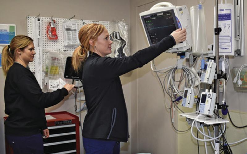 AMANDA KEMPER AND Kristi Splawn, both Registered Nurses, look over this equipment in the hospital’s emergency room. Tribune photo by Roy Sanders