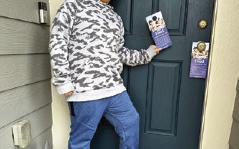 JAKE BARON is pictured putting out door hangers for the “Scouting for Food” event. The local Cub Scout Pack is participating in this event to gather food and donations for the Elizabeth Lutheran Church Pantry.