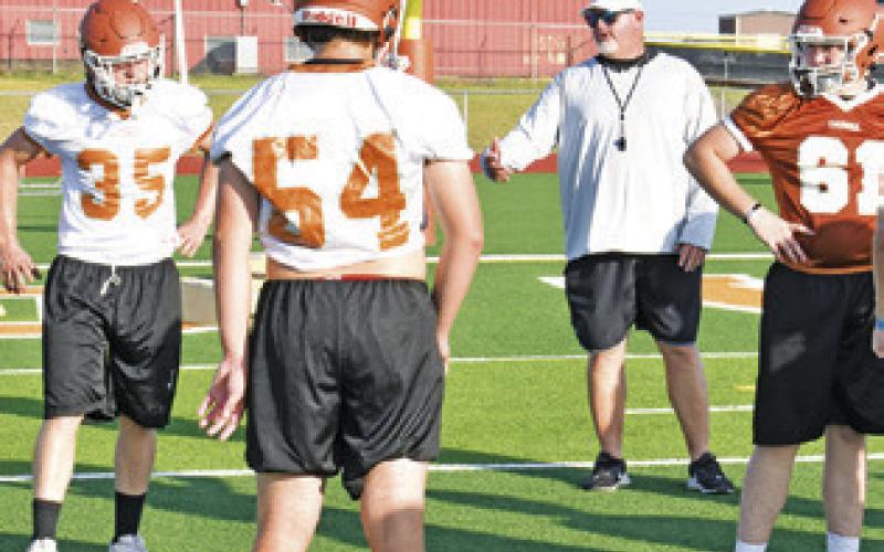 CALDWELL FOOTBALL PLAYERS listen to a point by new head coach Sean Witherwax at the Monday opening workout.