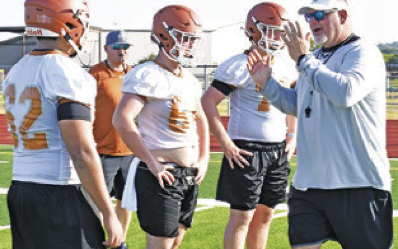NEW CALDWELL HEAD Coach Sean Witherwax talks to the lineman on Monday on the first day of fall practice at Hornet Stadium.