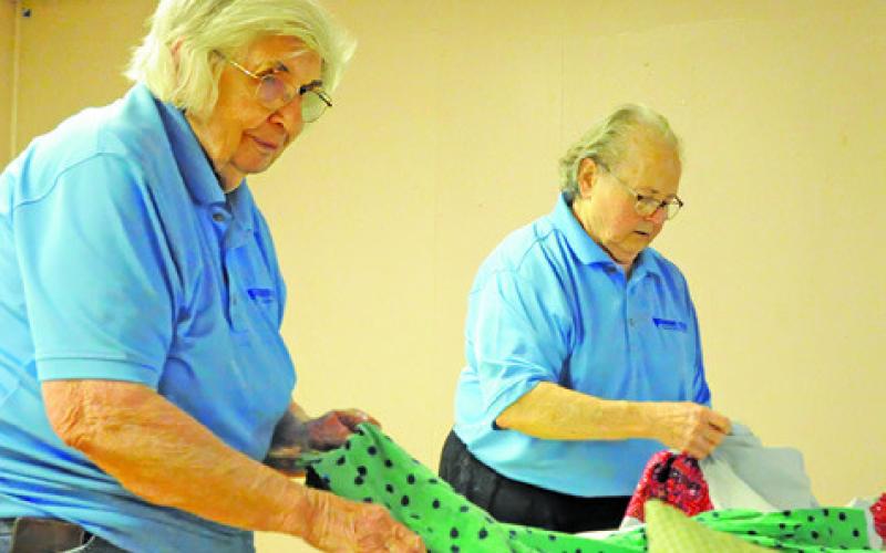 LYDIA FAUST AND ANN Sebesta fold shirts to place inside of Blessing Boxes for women battling breast cancer. Tribune photo by Denise Squier