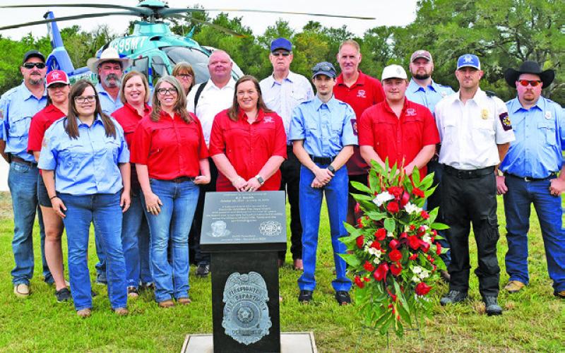 MEMBERS OF THE DEANVILLE Volunteer Fire Department gather around the monument on Saturday at the fire station helipad. -- Tribune photo by Roy Sanders