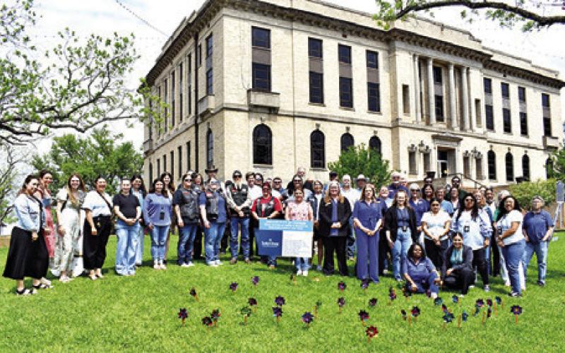 ATTENDEES OF THE CHILD Abuse Awareness and Prevention Month ceremony are pictured with the 39 pinwheels, planted to symbolize victims of child abuse in Burleson County. Tribune photo by Roy Sanders