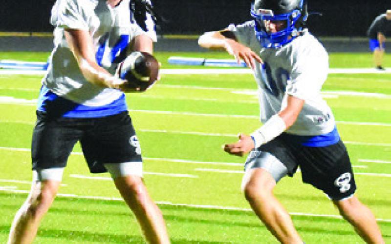 BRAYDEN MACIK hands off the ball to Kaden Clark during a Friday night practice.
