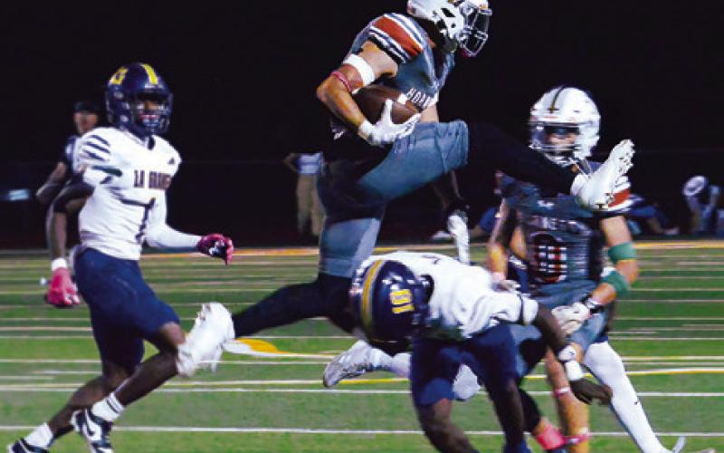 COY BECKA OF Caldwell leaps over this defender in the Hornets’ game against La Grange last Friday night. Tribune photo by Kim Hutcheson