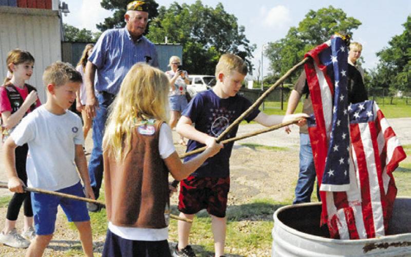AREA CHILDREN UNDER THE supervision of members of VFW Post 4458 retired these flags by burning on Flag Day, June 14, during a ceremony at the post. -- Tribune photo by Denise Squier