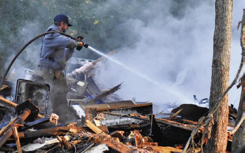A FIREFIGHTER WASHES down the debris at this fire on Friday, Aug. 15, on North Gray Street. See story page 3A.