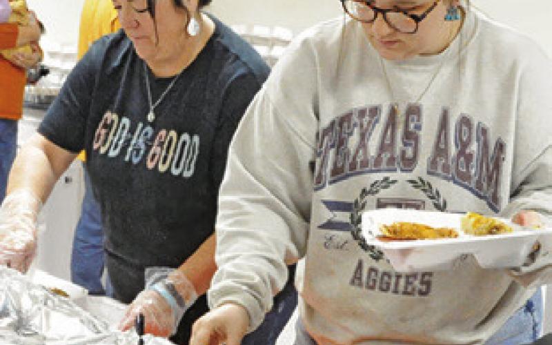 MEMBERS OF CALDWELL Assembly prepare plates of food for those attending a Thanksgiving lunch last Thursday afternoon. Tribune photo by Denise Squier