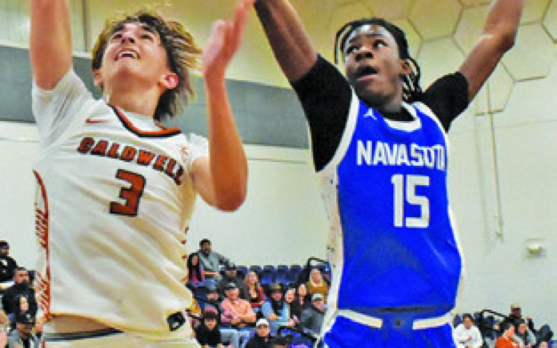 DYLAN CHAPMAN of Caldwell leaps high for this basket against Navasota. Tribune photo by Roy Sanders