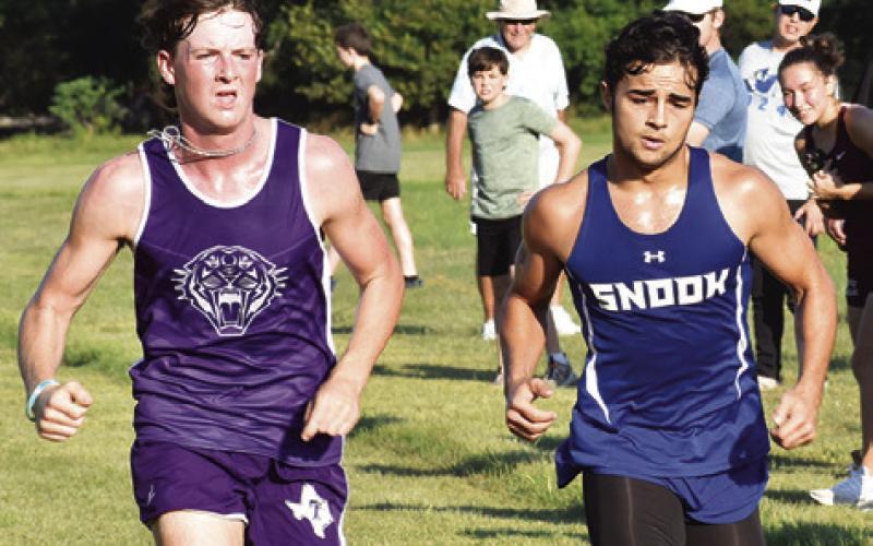 SNOOK’S TRISTEN YEN, right, battles with a Thrall runner for 15th place at last Saturday’s Caldwell Cross Country Invitational at Davidson Creek. Yen finished .13 of a second ahead of S. Clark from Thrall.