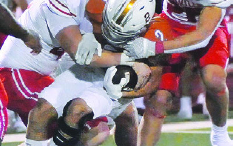 KORBIN BURNS is tackled by these Bellville defenders in Caldwell’s season finale. Tribune photo by Denise Squier
