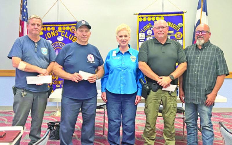 CBC LIONS PRESIDENT JOHANNA ELLIOTT presents checks to fire chiefs representing the nine Burleson County Volunteer Fire Departments this past Thursday.