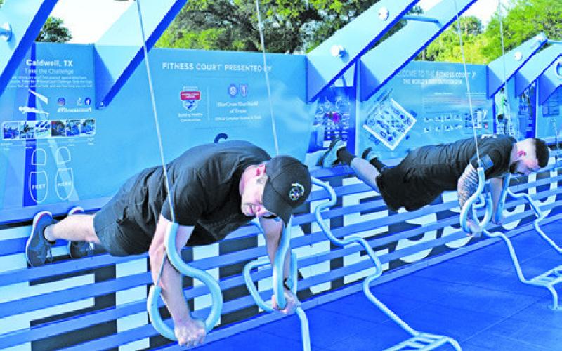 A DPS TROOPER and a Caldwell police officer participate in a fitness challenge at the new fitness court at Davidson Creek Park.