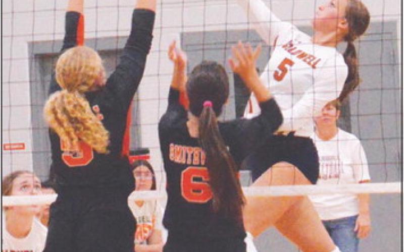 CALDWELL’S KYSEN TONEY hits the ball over two Smithville blockers during the Lady Hornet’s district win last Friday night.