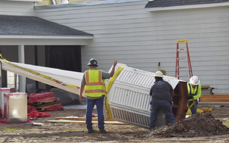 CREW MEMBERS WORK on the steeple at New Tabor Brethren Church. Church members gathered to see it installed. Tribune photo by Roy Sanders