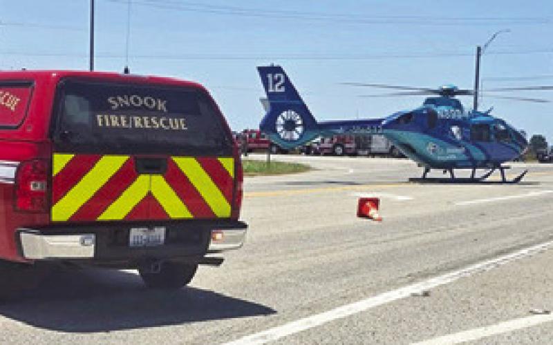A HELICOPTER lands at the scene of this accident on F.M. 50 and F.M. 60 on Tuesday. Photo courtesy of Snook VFD