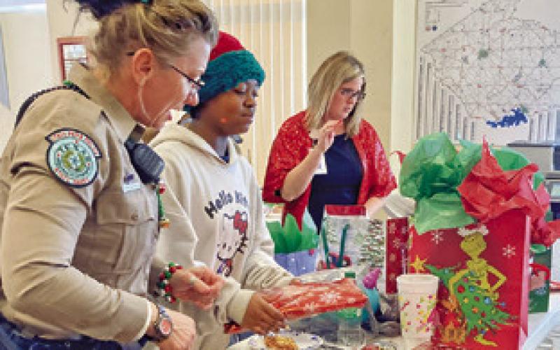 CHILDREN WRAP PRESENTS AT THE Caldwell Fire Station as part of the 2024 Shop with a Cop event. Tribune photo by Sabine Lazo