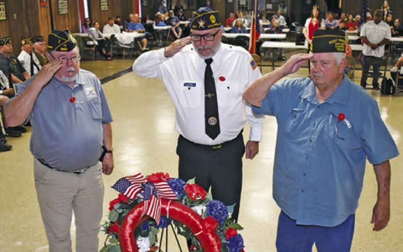 THE MEMORIAL DAY wreath is saluted at the Monday ceremony. Pictured from left are John Mayson of the DAV post, Lee Hoermann, representing the American Legion, and Donny Wood with the VFW.