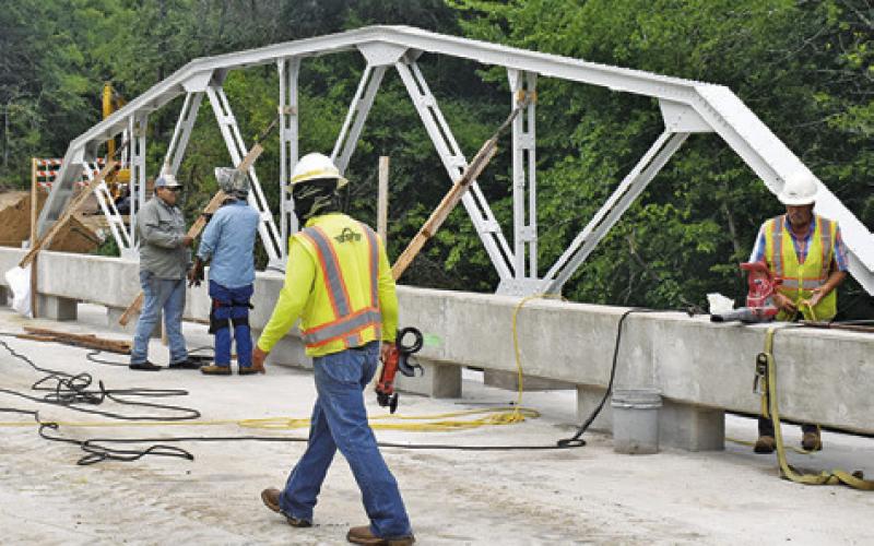 BRIDGE WORK CONTINUES on County Road 146 on Thursday, July 3. The old trusses were preserved and added onto the bridge. Tribune photo by Roy Sanders