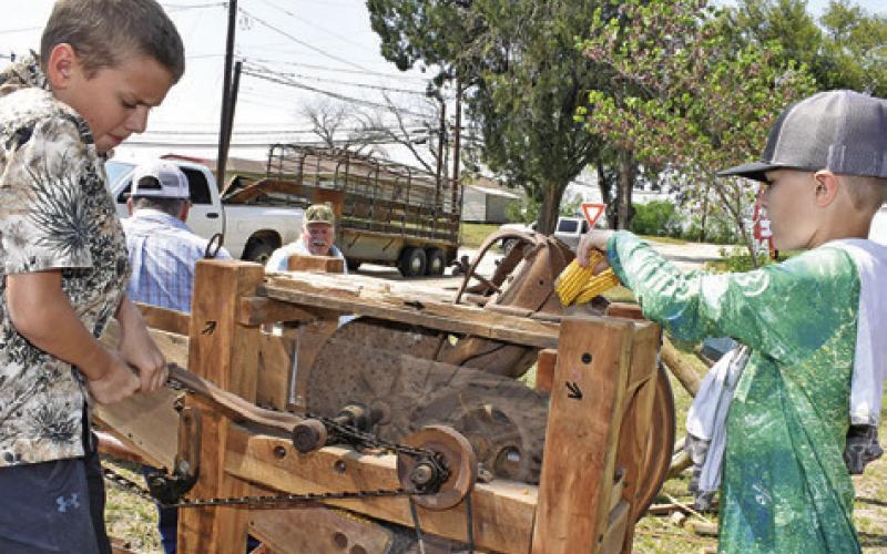 RHETT HARTMAN AND Brooks Urbanosky try out this corn grinder at a demonstration on Saturday, March 28, at the Burleson County Czech Heritage Museum’s annual Heritage Day.
