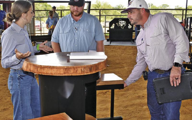 LYDIA HICKS DISPLAYS her project in the Ag Mech show as judges Marshall Miles and Kenneth Goines listen and observe.