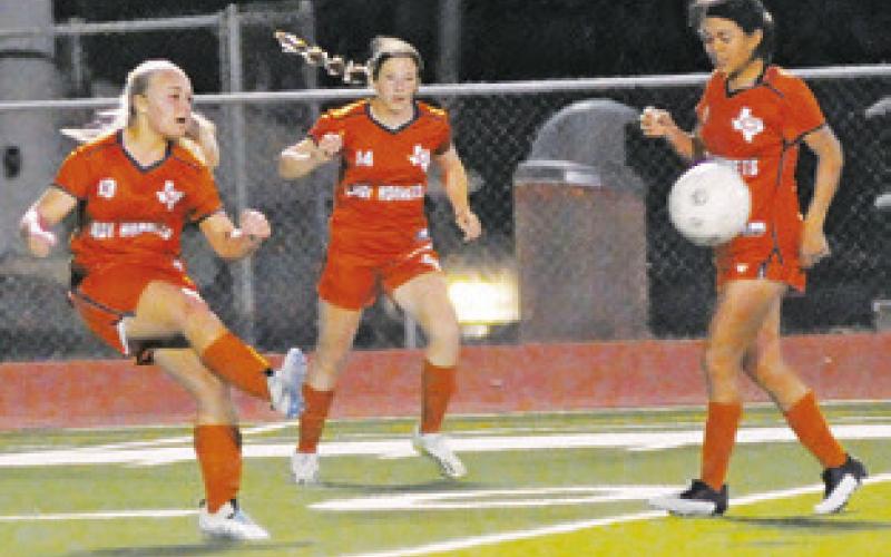 CALDWELL’S GRACELYNN SEE kicks the ball downfield while teammates Adeline Hicks and Lola Rogriguez look on.