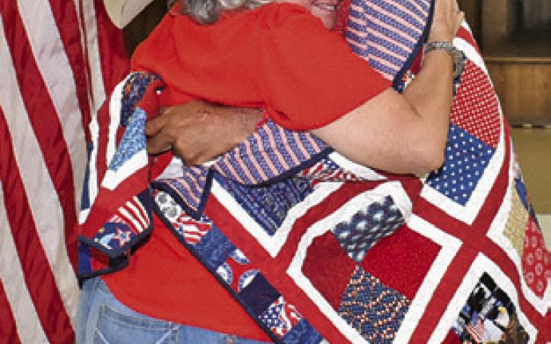SHARON COLLEY hugs Robert Norris after he receives his Quilt of Valor at the VFW.