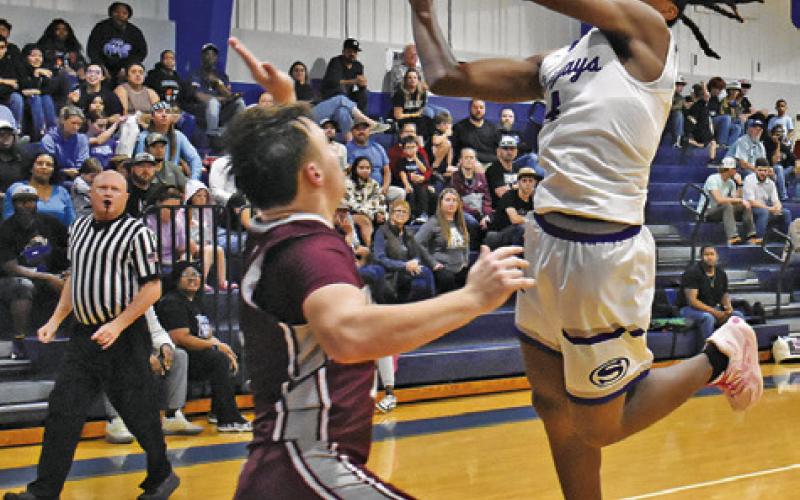 JOHN CARR LUNGES for this shot against Iola in Snook’s win. Tribune photo by Roy Sanders