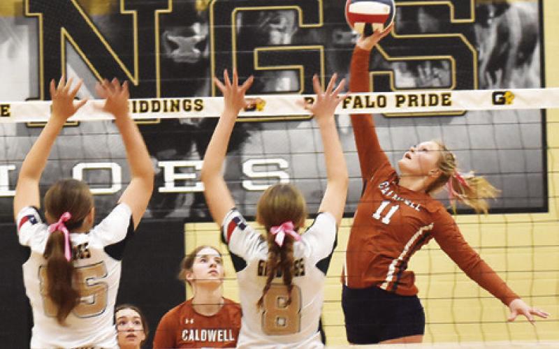 CALDWELL’S REESE MCMANUS hits the ball over Giddings’ blockers, Caedon Melcher and Aliza Rodriguez, during the Caldwell-Giddings district match last Friday night. Tribune photo by Roy Sanders