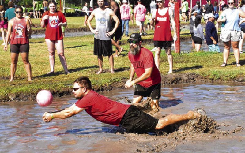 A MUD VOLLEYBALL player lunges for the ball right before he falls into a big mess.