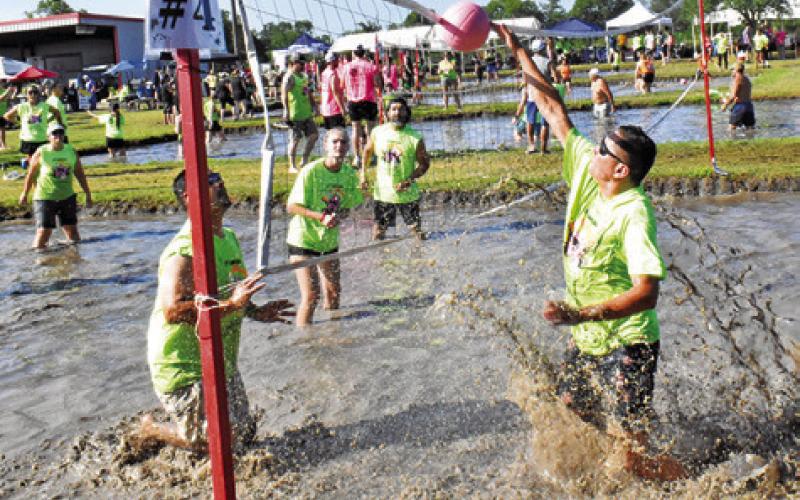 MUD VOLLEYBALL players go for the ball at the net on Saturday at the Hog Slash in Snook.