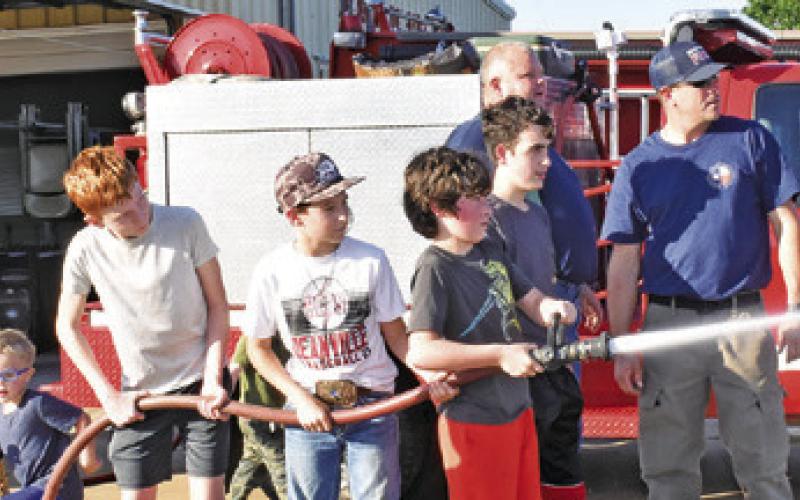 FUTURE FIREFIGHTERS SPRAY water under the supervision of Nathan Flippin and Jeff Baldwin on Saturday at the Deanville Volunteer Fire Department’s Community Night Out.
