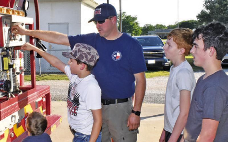 JEFF BALDWIN OF Deanville Volunteer Fire Department shows these boys one of the fire trucks at the department’s Community Night Out on Saturday, May 2, at the fire station.