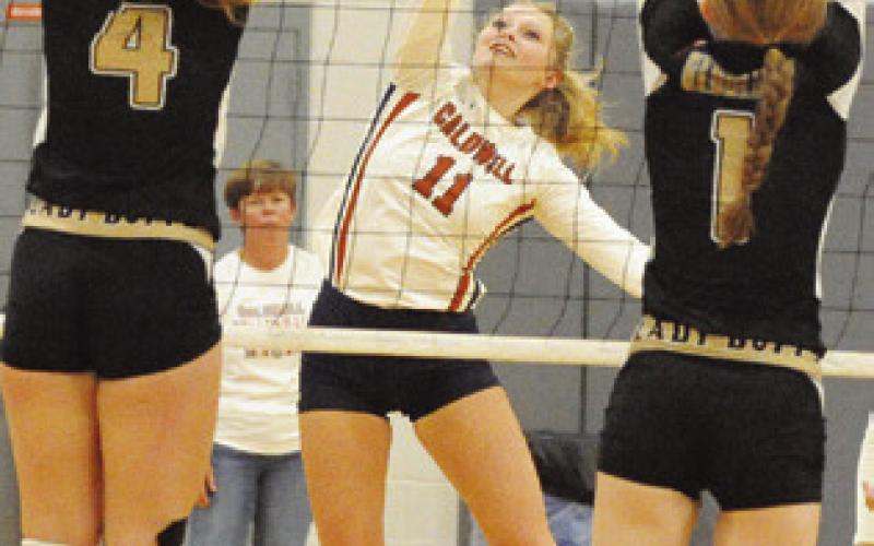 LADY HORNET REESE McManus hits the ball through the outstretched arms of Karleigh Blansit and Alyssa Brade during Caldwell’s match with Giddings on Friday. -- Tribune photo by Denise Squier
