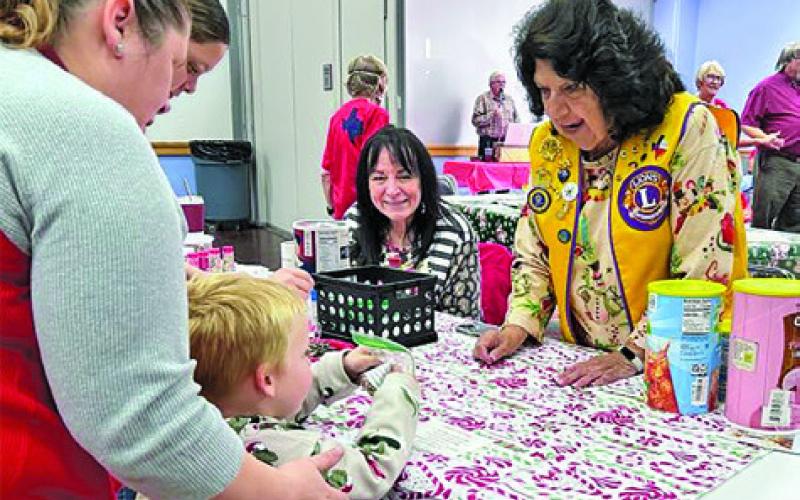 LIONS CLUB MEMBERS helped bring some Christmas cheer to children attending the Harrie P. Woodson Memorial Library’s “Miracle on Main.”