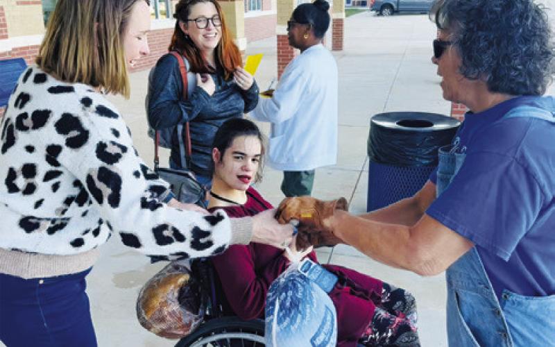 SNOOK ISD GIVES ITS team members hams and turkeys as a “thank you” for their work within the district. Pictured is Snook ISD board member Dana Yezak giving out a turkey.