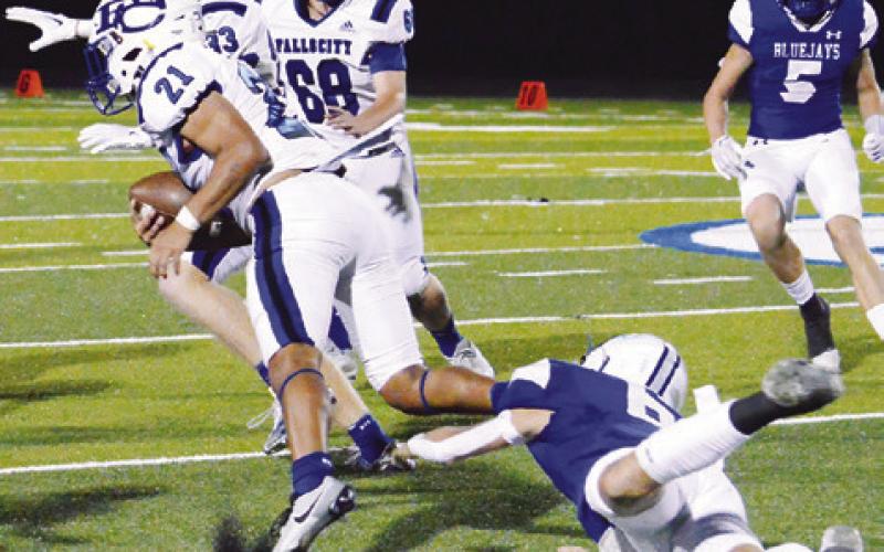 A FALLS CITY player breaks away from Snook defenders in last Friday game in Snook. Snook lost 28-0 and faces Yorktown this Friday in Yorktown.