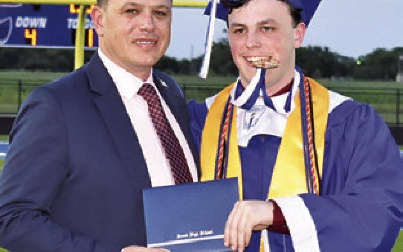 ADAM JANAC presents his son Ethan Janak his diploma at the Snook High School Commencement on Friday at Bluejay Stadium.