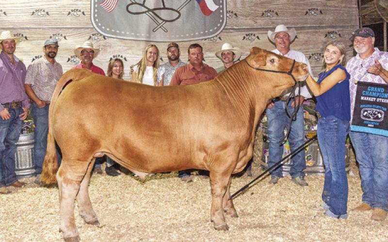 THE GRAND CHAMPION Market Steer was exhibited by Madalyn Faust. She is pictured with Jeff Baldwin, Branden Faust, Stephen Hibbeler, Margaret Hibbeler, Holdyn Novosad, Cody Novosad, Brad Novosad, Hank Herrmann, Jeff Brown and Josh Hill. Photo courtesy of Jeffries Livestock Marketing