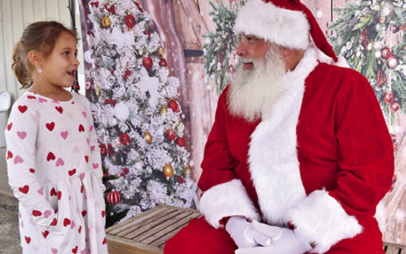 SANTA CLAUS VISITS with a girl on Sunday morning at the Farmers Market in Somerville. The Christmas theme was enjoyed by visitors.
