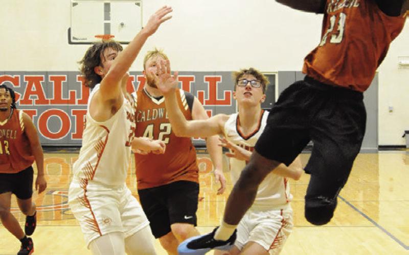 SHAGARIUS HARRISON LEAPS high for this shot as varsity’s Koy Macik and Caden Zboril defend. Also pictured for the alumni are Deautre Burns and Chase Stewart. Tribune photo by Denise Squier