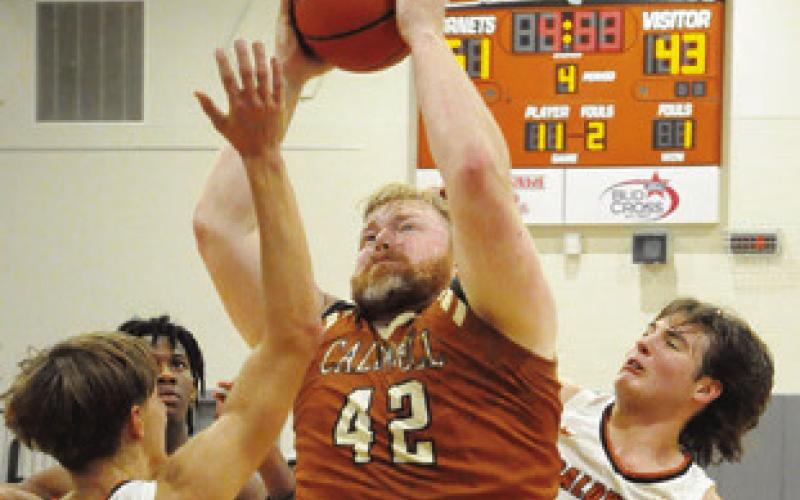 THE ALUMNI’S CHASE Stewart shoots as the varsity’s Dylan Chapman and Koy Macik defend in last Friday’s game. Tribune photo by Denise Squier