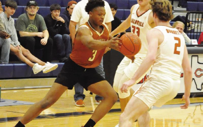 JUNIOR MATHIS OF the alumni team dribbles the ball around the varsity’s Koy Macik and Ryan See. The varsity won 65-55. Tribune photo by Denise Squier