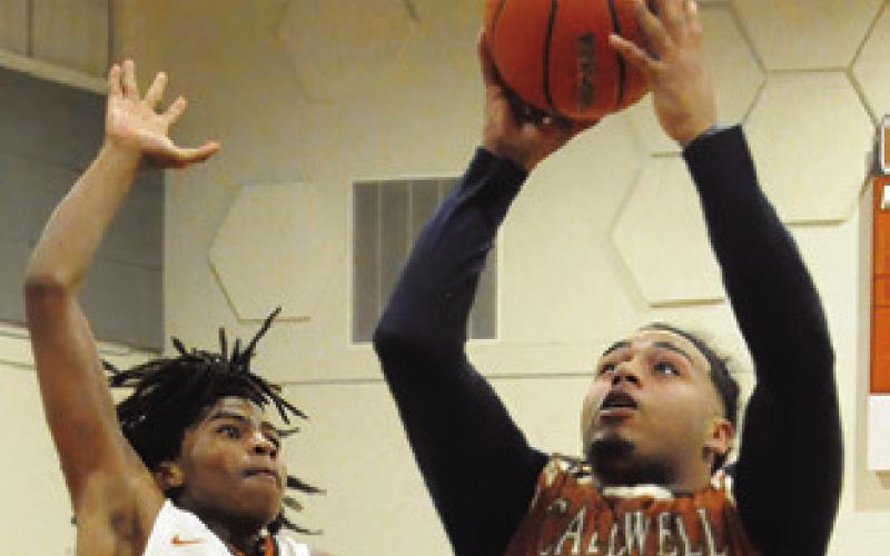 ALUMNI DELVIN Morris shoots as varsity player Jaden Hagan defends. Tribune photo by Denise Squier