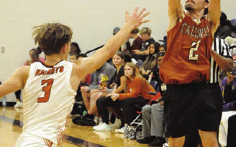 CALDWELL’S DYLAN Chapman moves in to block as the alumni’s Bobby Lerouax shoots in the varsity versus alumni game. Tribune photo by Denise Squier
