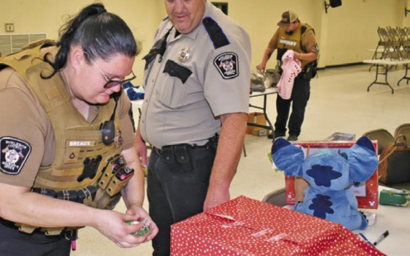 SHERIFF’S DEPUTIES ASSIST with wrapping presents during Shop With A Cop on Friday at the Burleson County Expo Center.