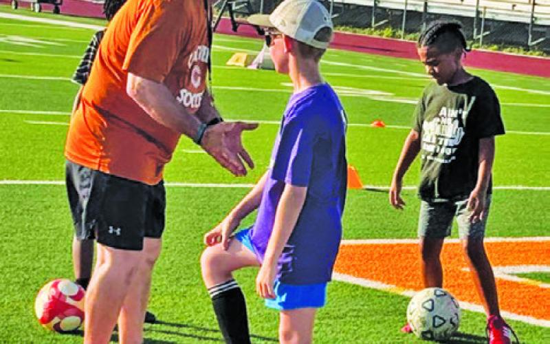 HORNET SOCCER COACH Burt Yates instructs athletes at this summer’s Hornet Soccer Camp -- working on skills and having fun.