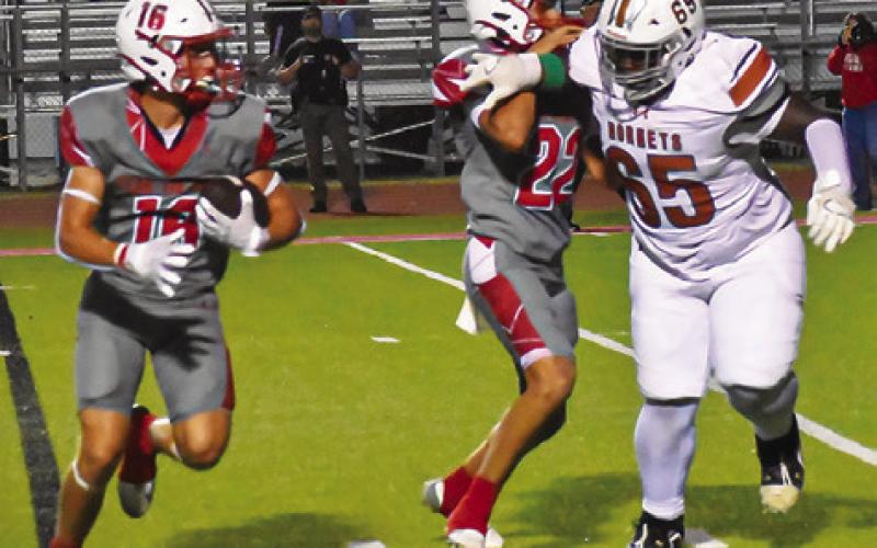 KAYDEN ROBERTSON OF Caldwell pursues this Bellville ball carrier in the Hornets season finale last Friday in Bellville. Tribune photo by Roy Sanders