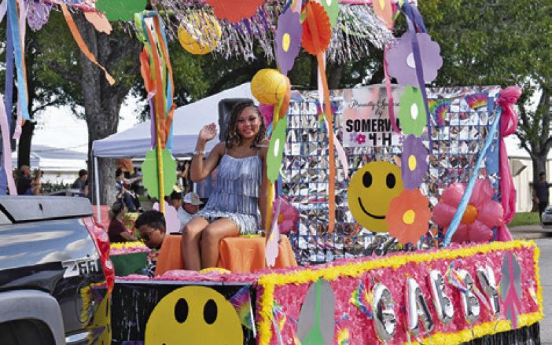 QUEEN CANDIDATE GABRIELLE Jackson waves to the crowd at last Saturday’s Burleson County Fair Parade from her 60s inspired float featuring the fair’s “Decades of Fun” theme. Tribune photo by Roy Sanders