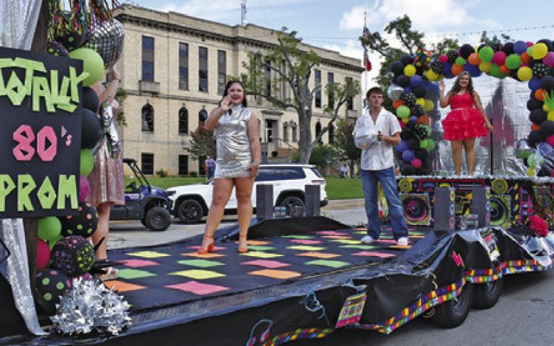 QUEEN CANDIDATE MIRANDA Polasek waves to the crowd at last Saturday’s Burleson County Fair Parade from her 80s inspired float featuring the fair’s “Decades of Fun” theme. Tribune photo by Roy Sanders